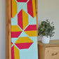 Flourishing quilt in two colour version of red and yellow on a light green background on a quilt ladder