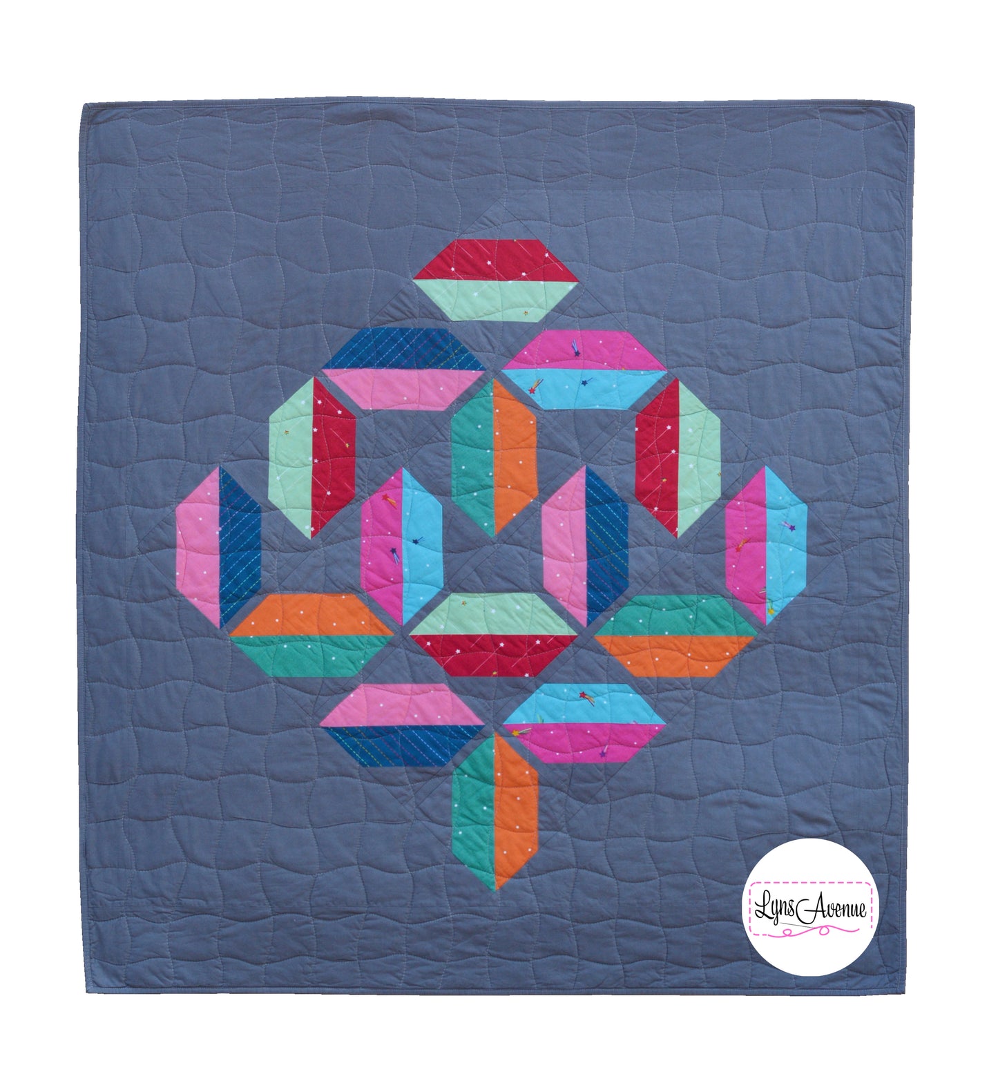Flourishing quilt in scrappy colours, red, blue, orange, green and pink on a grey background