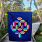 Flourishing quilt pattern in scrappy colours pink, peach, yellow, blue, green and lime on a navy blue background with trees in the background